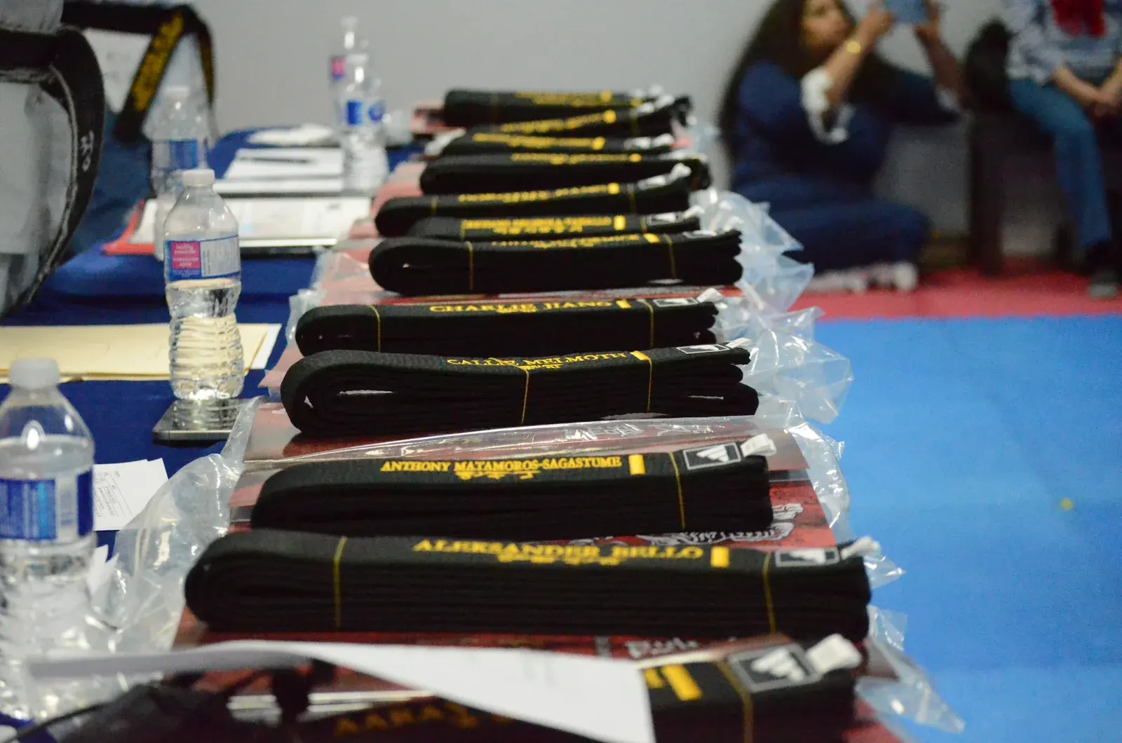 New black belts, embroidered with names, laid out on a table