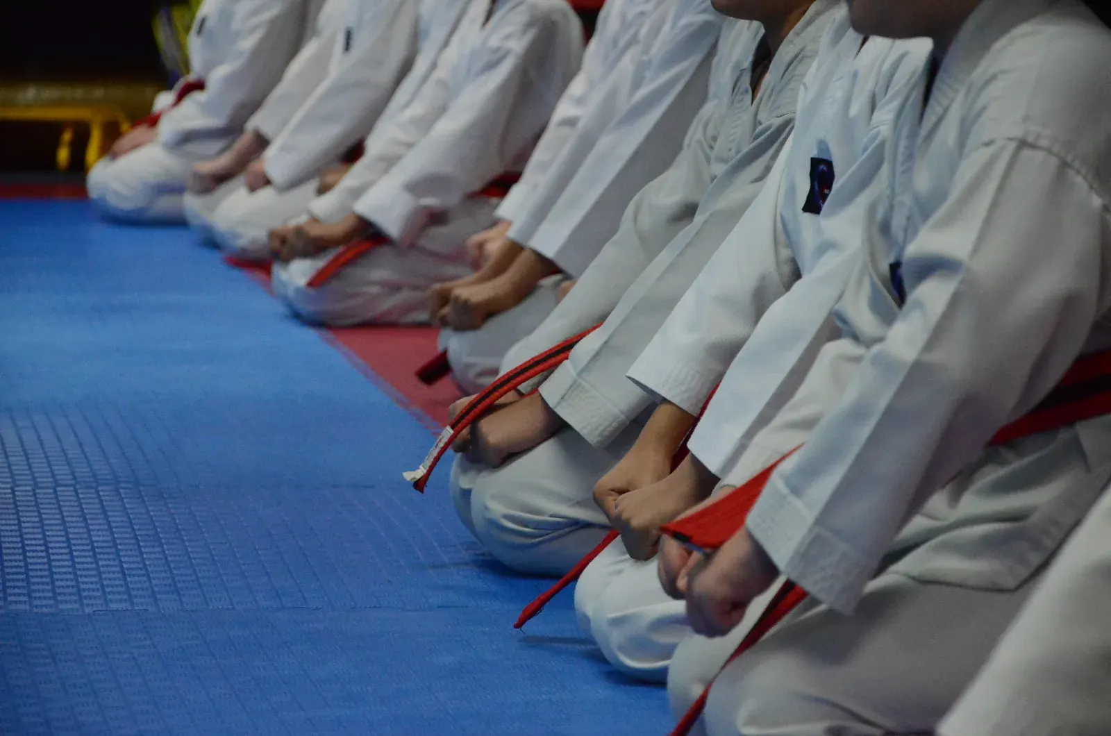 A row of students kneeling in their uniforms with their hands on their knees