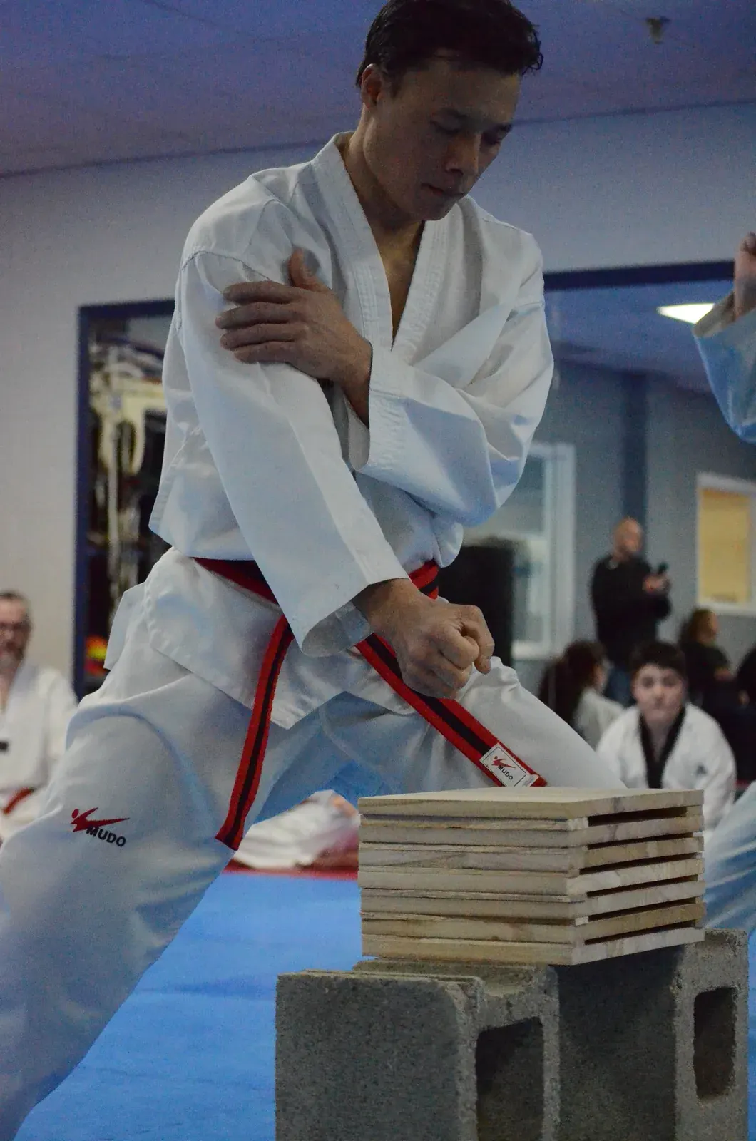 A student breaks boards on cinder blocks at a black belt test