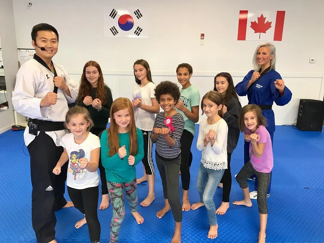 Birthday party guests strike a fighting stance with two instructors on the blue mats