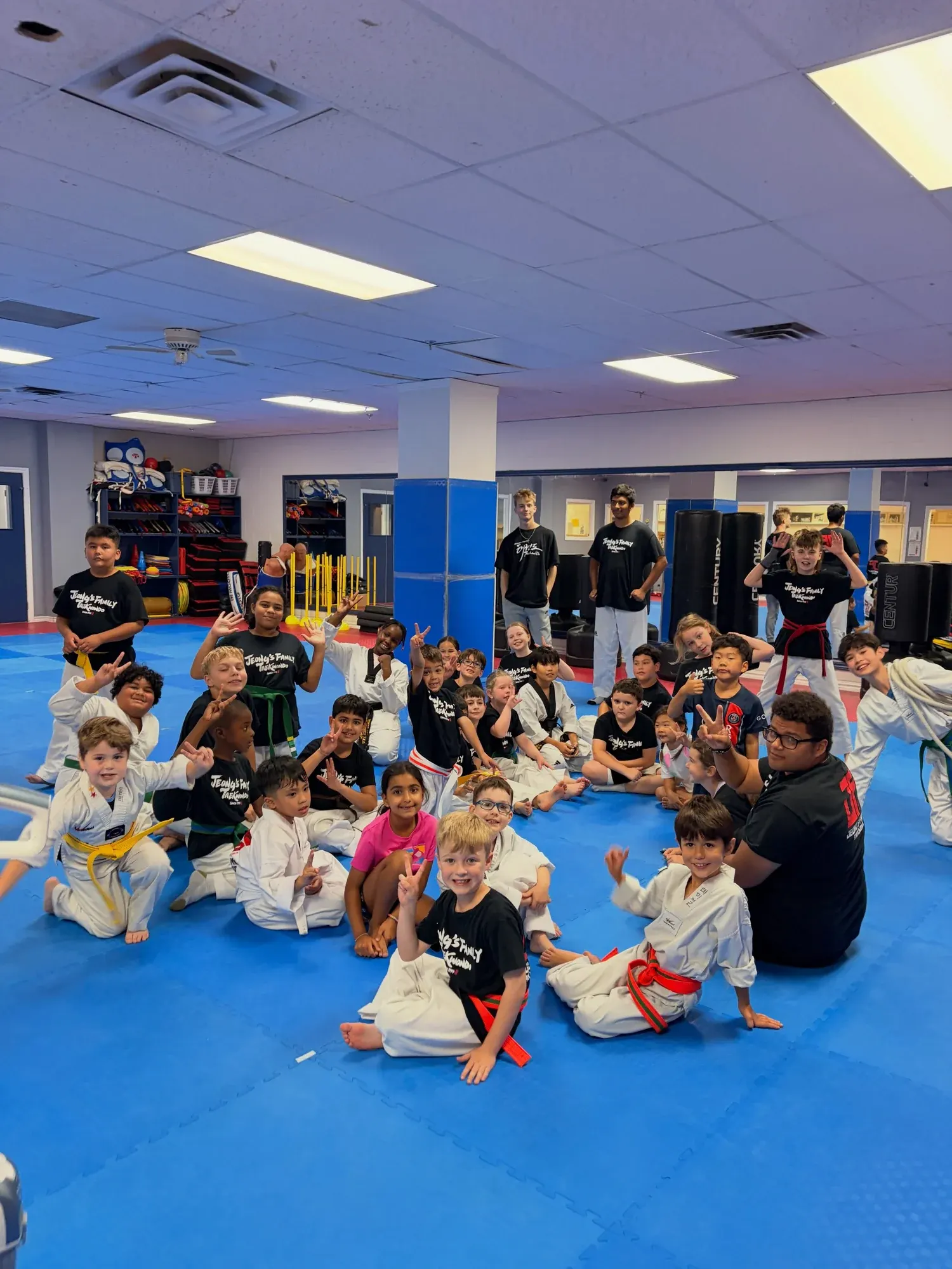 A big group of campers on the mat, many of them making peace signs