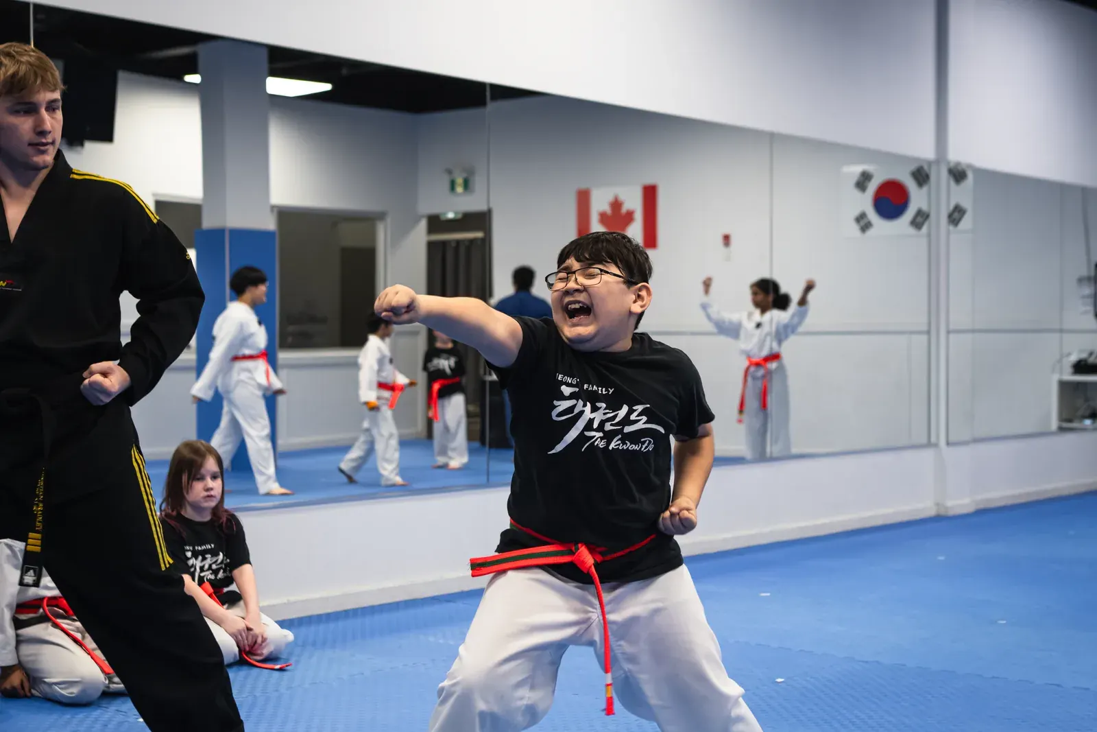 A smiling student in a Jeong's t-shirt throws a punch in the Niagara Falls studio