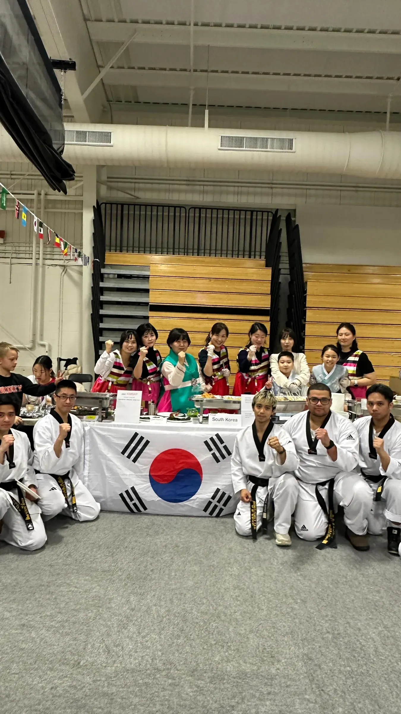 Our masters and instructors with a group around a Korean flag at Ridley College