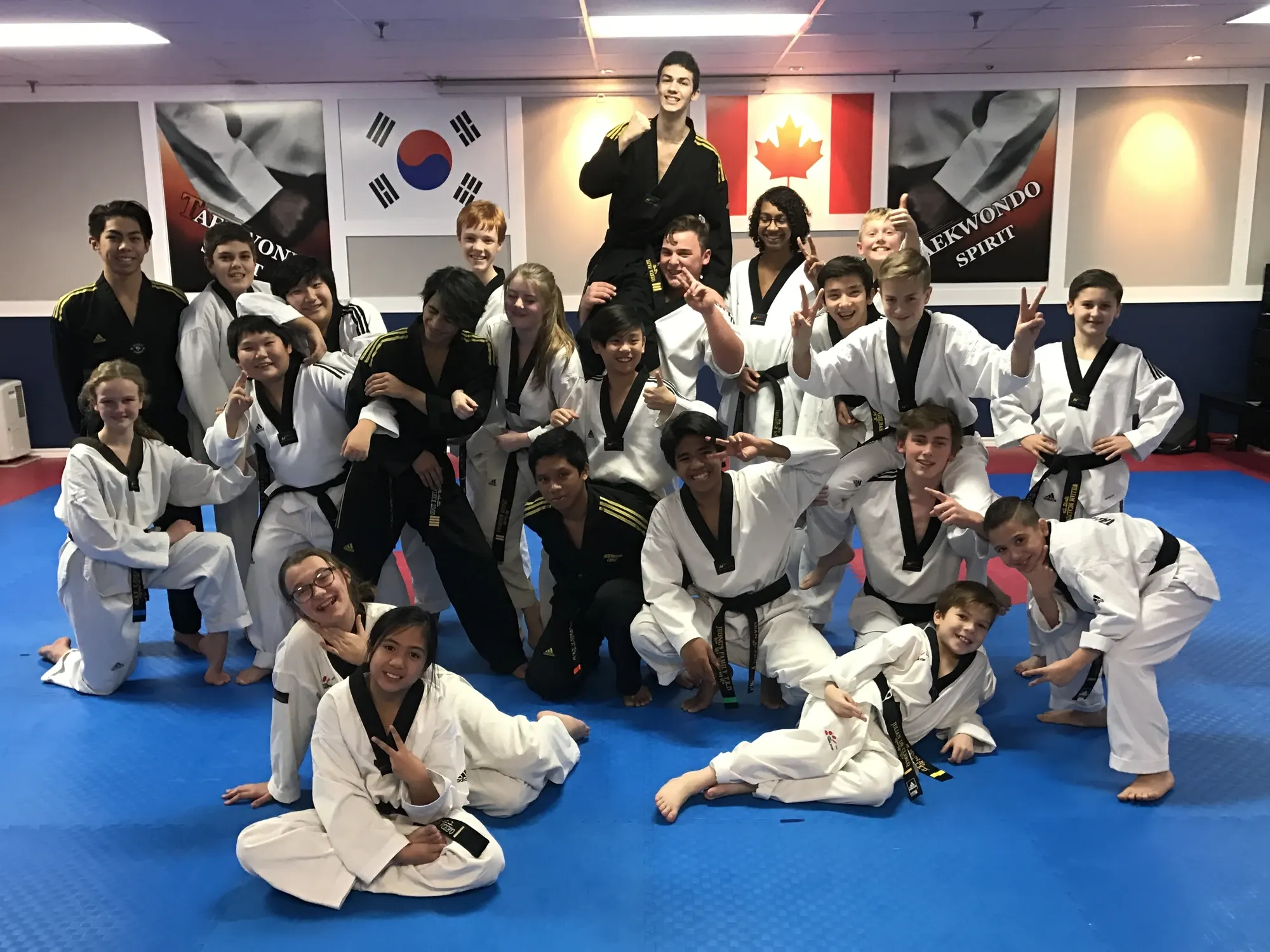 Black belt students and instructors pose together on the mats, smiling