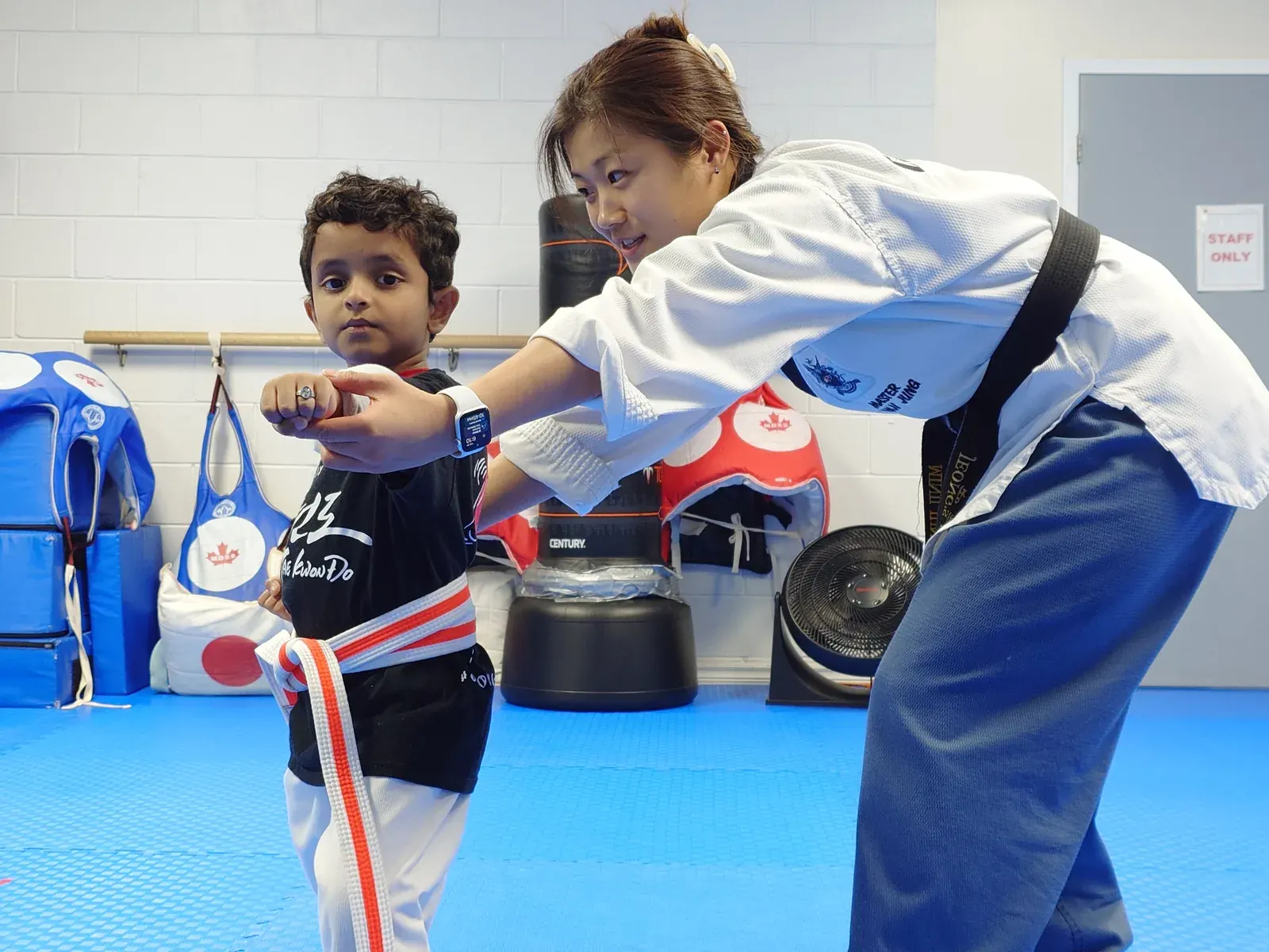 An instructor guides a young student through a punch