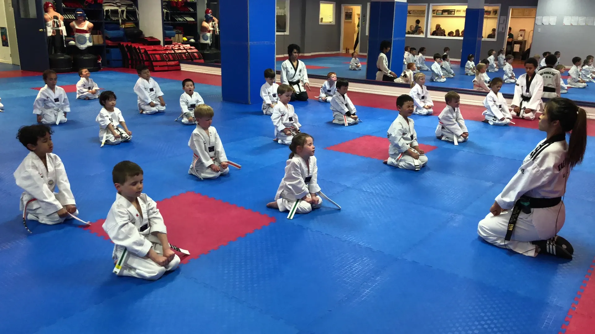 Little Tigers kneel in rows on the blue and red mats at the Niagara Falls school, with their instructor