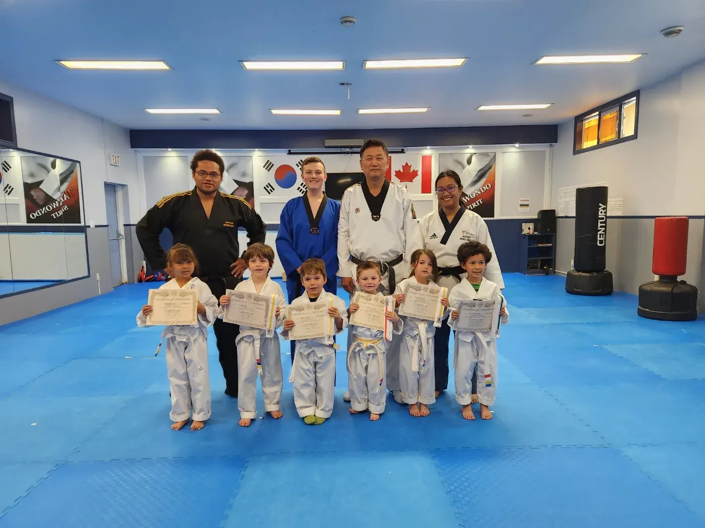 Little Tigers hold their certificates after a belt test, with their instructors