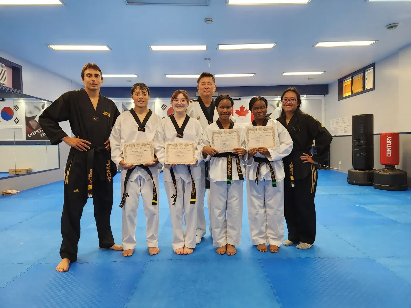 New black belts hold their certificates beside their instructors