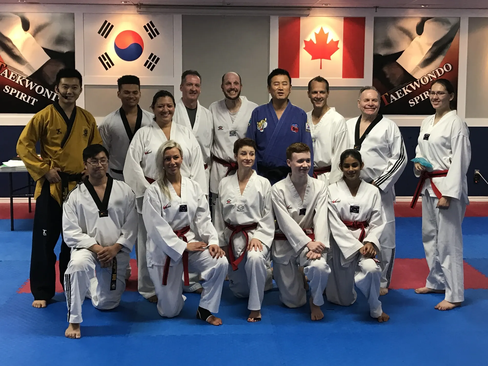 Teen and adult students with their instructors, in front of the Korean and Canadian flags