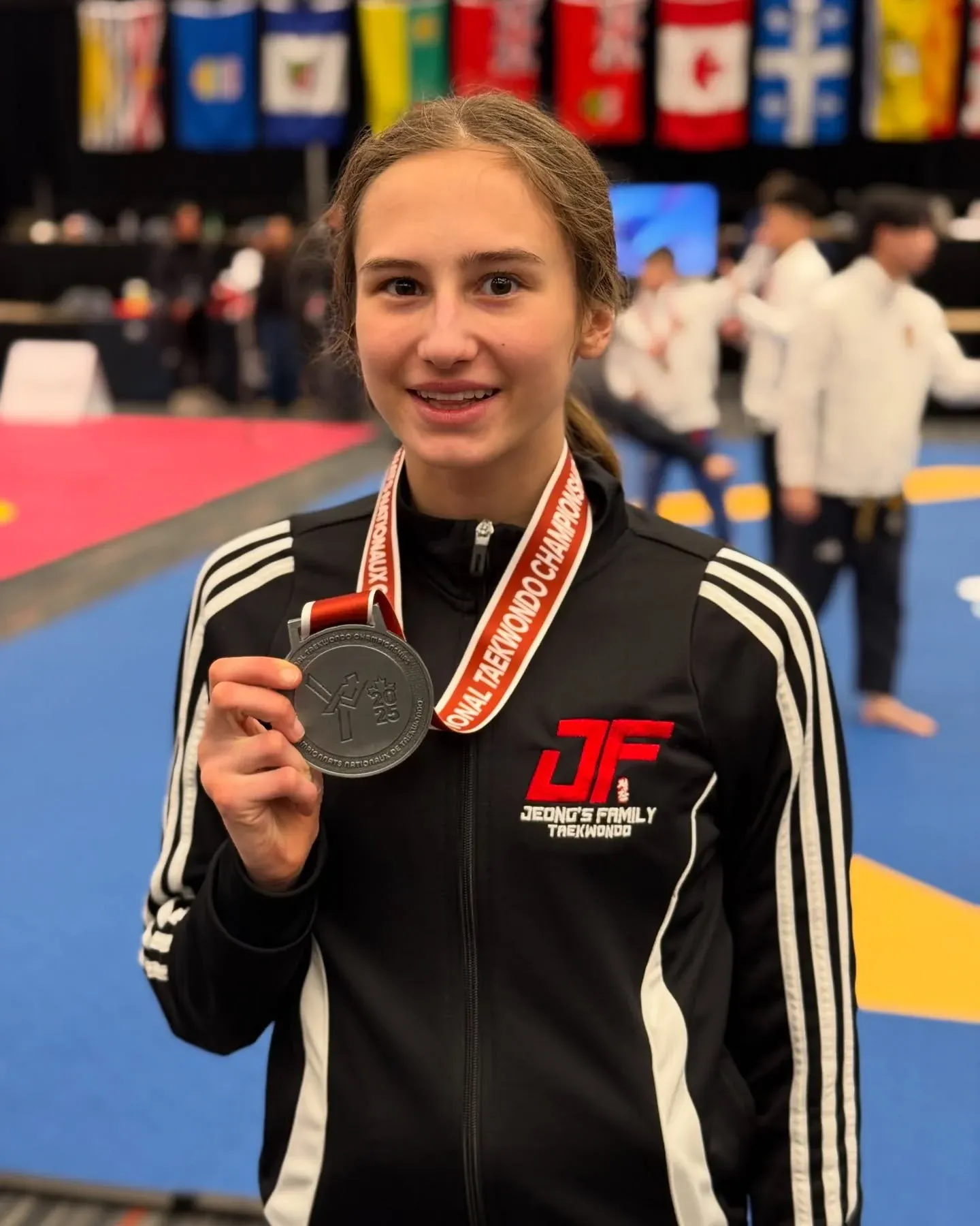 Violet Yerich in a Jeong's Family Taekwondo jacket, holding up her medal from the Taekwondo Canada National Championships